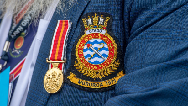 An embroidered badge on a suit jacket indicating service in Mururoa