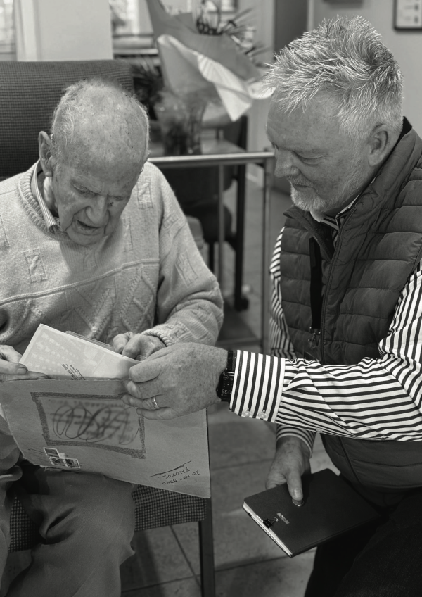 Niall Shepherd assisting an older man with a large envelope