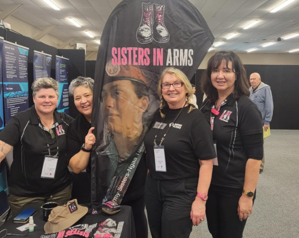 Four women at an event table showcasing Sisters in Arms